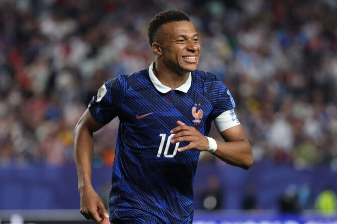Kylian Mbappé im blauen Frankreich-Trikot mit der Nummer 10, lachend auf dem Spielfeld