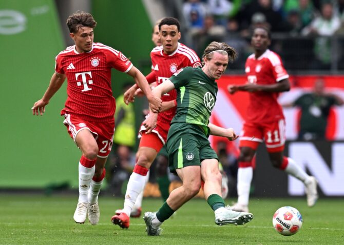 Wolfsburgs Patrick Wimmer treibt den Ball nach vorne, während Tom Bischof vom FC Bayern München energisch nachsetzt. Die Szene stammt aus dem Bundesliga-Spiel zwischen dem VfL Wolfsburg und dem deutschen Rekordmeister am 9. Mai 2026 in der Volkswagen Arena. Oliver Hardt / Getty Images