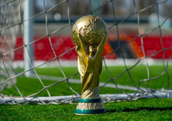 Eine Nachbildung des WM-Pokals steht im Tor auf dem Rasen eines Fußballstadions. Das goldene Original wird bei der FIFA Fußball-Weltmeisterschaft 2026 in den USA, Mexiko und Kanada vergeben. (Copyright Depositphotos.com)