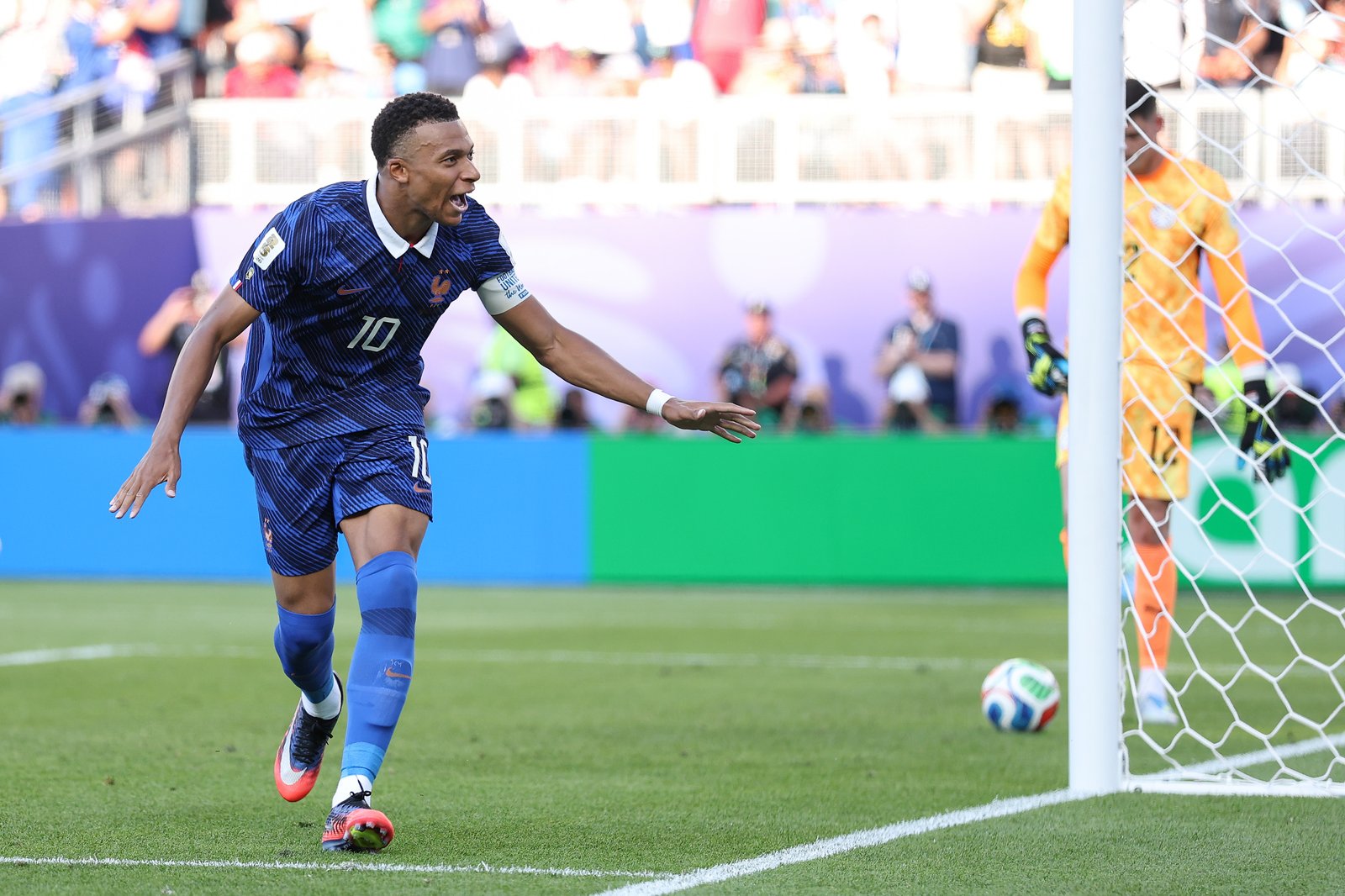 Kylian Mbappé feiert im Achtelfinale der WM 2026 seinen Treffer für Frankreich gegen Paraguay direkt neben dem Tor, während der geschlagene paraguayische Torwart im Hintergrund steht. Der französische Kapitän läuft mit ausgebreiteten Armen jubelnd am Netz entlang. Aufgenommen am 4. Juli 2026 im Philadelphia Stadium. Dan Mullan / Getty Images North America via Getty Images