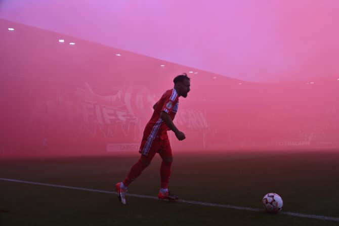 HALLE, DEUTSCHLAND – 16. AUGUST: Ein Ultra des Halleschen FC hält vor dem DFB-Pokalspiel gegen den FC St. Pauli am 16. August 2024 in Halle eine brennende Pyrofackel in die Höhe. (Foto: Oliver Hardt/Getty Images)
