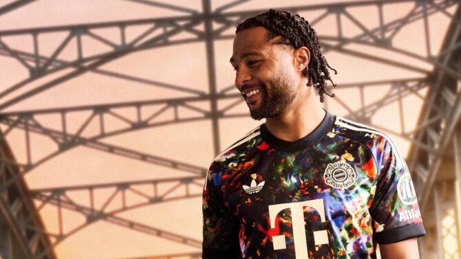 Serge Gnabry vom FC Bayern München präsentiert das neue adidas Wiesn Trikot 2026 mit floralem Allover-Print und Telekom-Logo in Creme. (Foto: adidas)