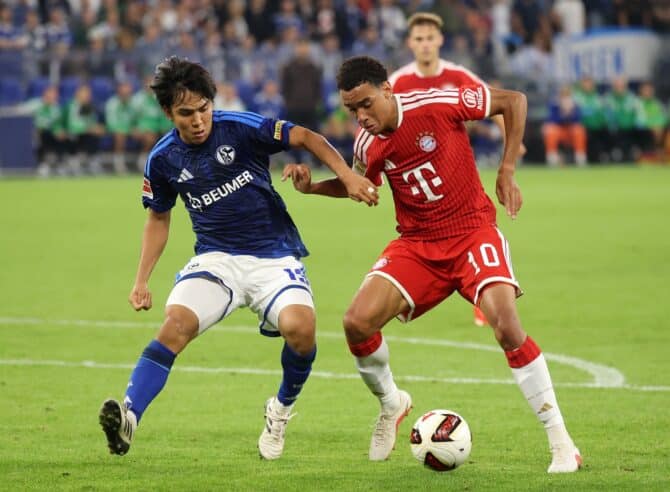 Jamal Musiala behauptet den Ball im Duell mit Satoshi Tanaka. Der Offensivspieler des FC Bayern München setzt sich am 5. September 2026 in der Veltins Arena im Bundesliga Spiel gegen den FC Schalke 04 durch. (Alex Grimm / Getty Images Europe via Getty Images)