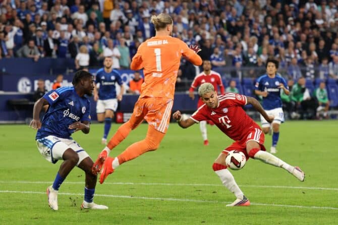 Loris Karius pariert am 5. September 2026 in der Veltins Arena den Abschluss von Luis Díaz. Der Torhüter des FC Schalke 04 hält den Ball fest, während Junior Dina Ebimbe den Angreifer des FC Bayern München im Bundesliga Spiel unter Druck setzt. (Alex Grimm / Getty Images Europe via Getty Images)